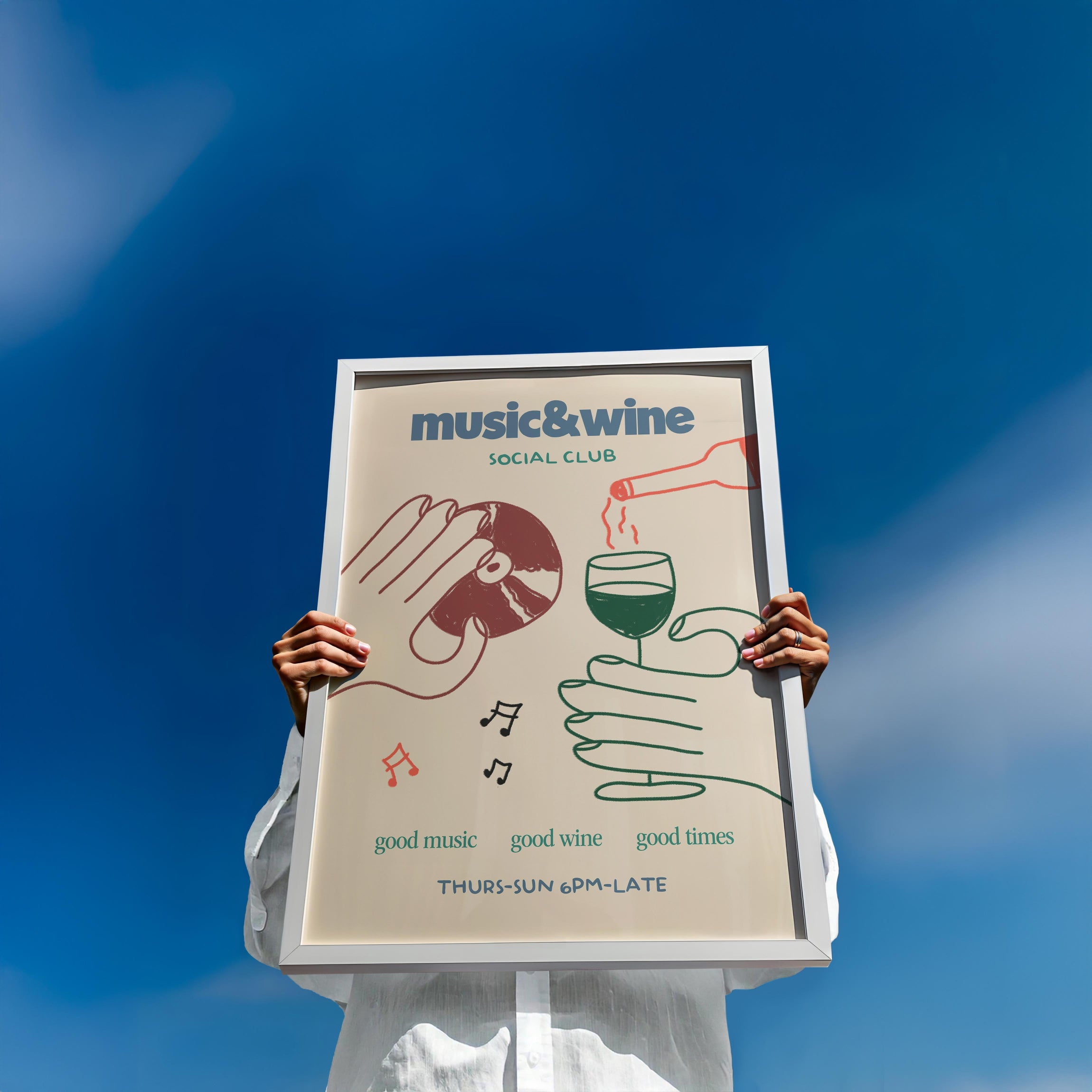 hands holding a white frame of music & wine social club print with a blue sky background